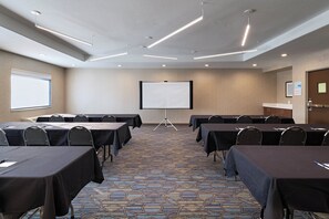 A conference room with tables, chairs, a projector screen, and a carpeted floor. - Holiday Inn Express Hotel & Suites Cedar Park by IHG (Cedar Park)