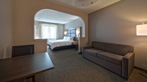 Una habitación de hotel con cama, sofá, escritorio y ventana con cortinas.