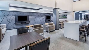 Un interior moderno con zona de comedor, sofás, televisor y cocina.