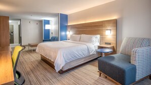 Moderni hotellihuone, jossa on suuri sänky, työpöytä, tuoli ja pieni pöytä.