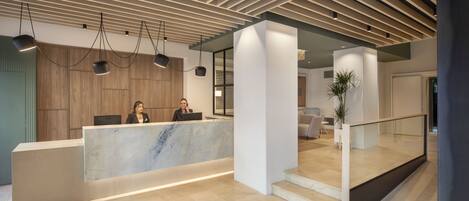 A modern reception area with a marble counter, wooden paneling, and pendant lighting.