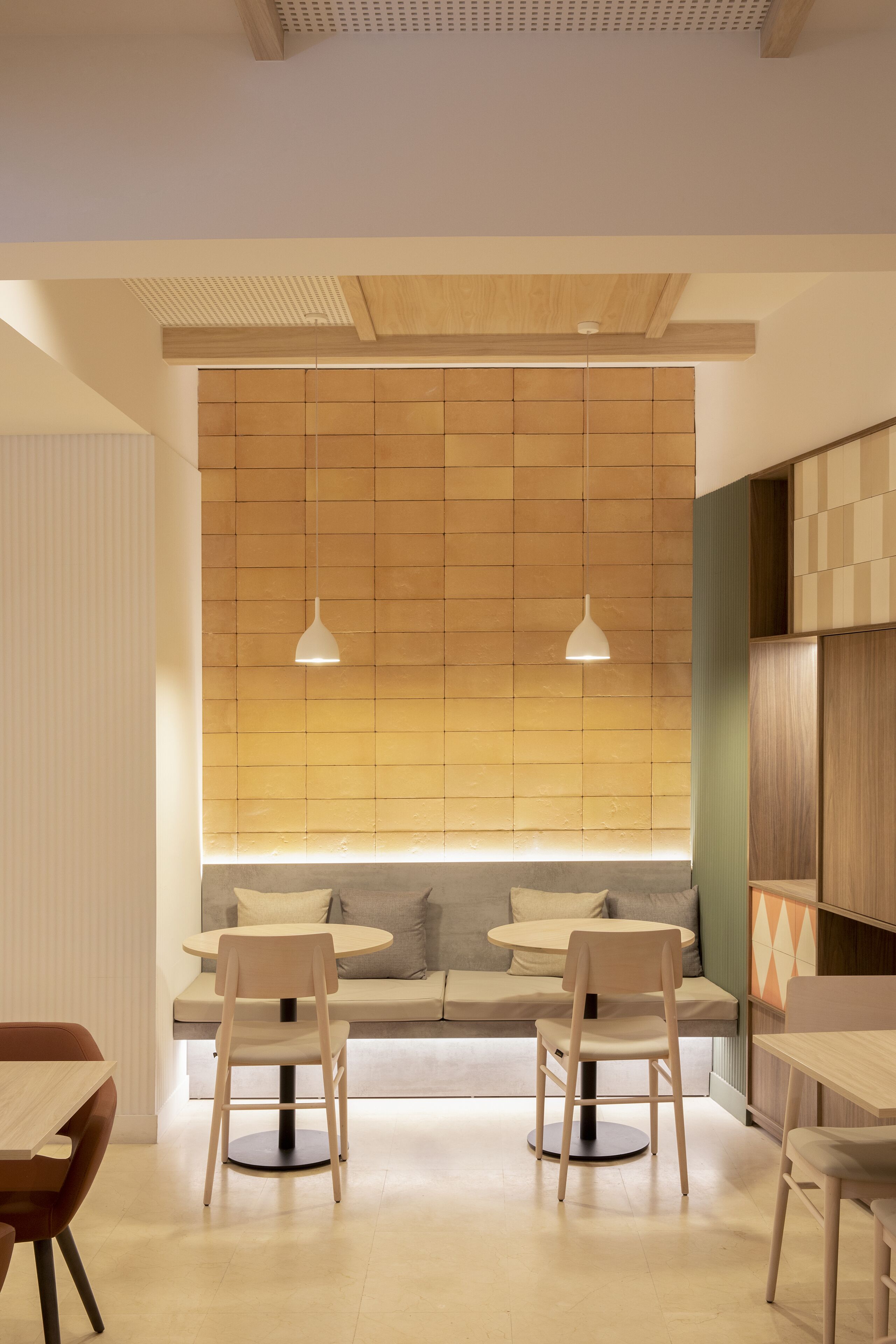 Un comedor moderno con dos mesas redondas, sillas e iluminación colgante.