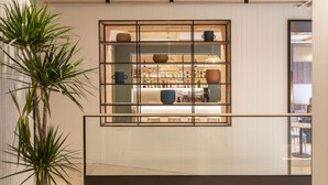 A modern interior with a wooden ceiling, a glass railing, and a view of a bar area. - Grupotel Gravina (Barcelona)