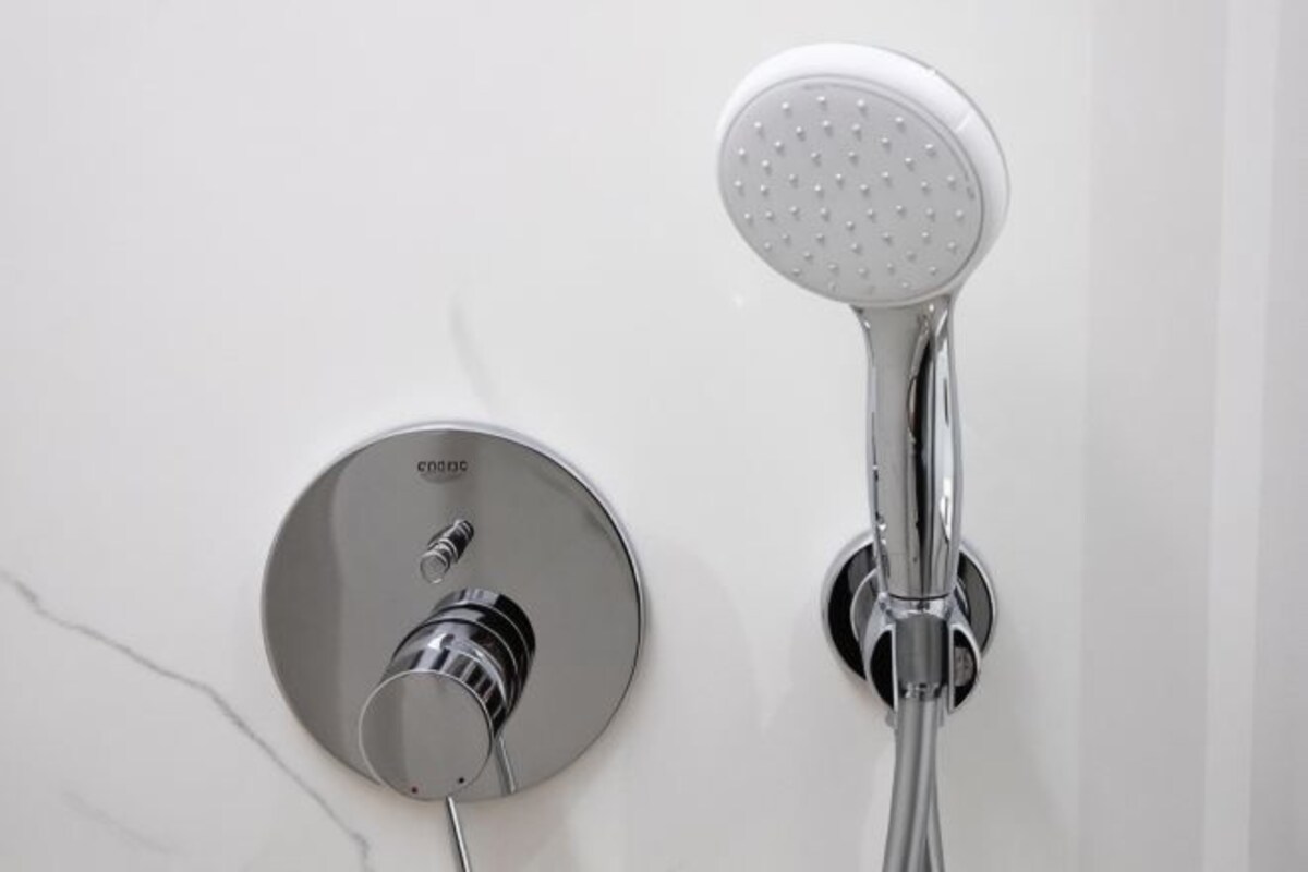 A wall-mounted shower with a handheld showerhead and a fixed showerhead.
