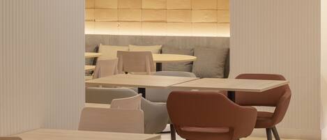 A modern dining area with a wooden wall, a hanging light fixture, and a seating arrangement.