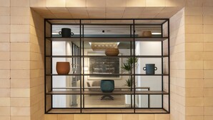 A modern interior with a central seating area featuring a round table and chairs, flanked by a wall-mounted shelf with decorative items. - Grupotel Gravina (Barcelona)