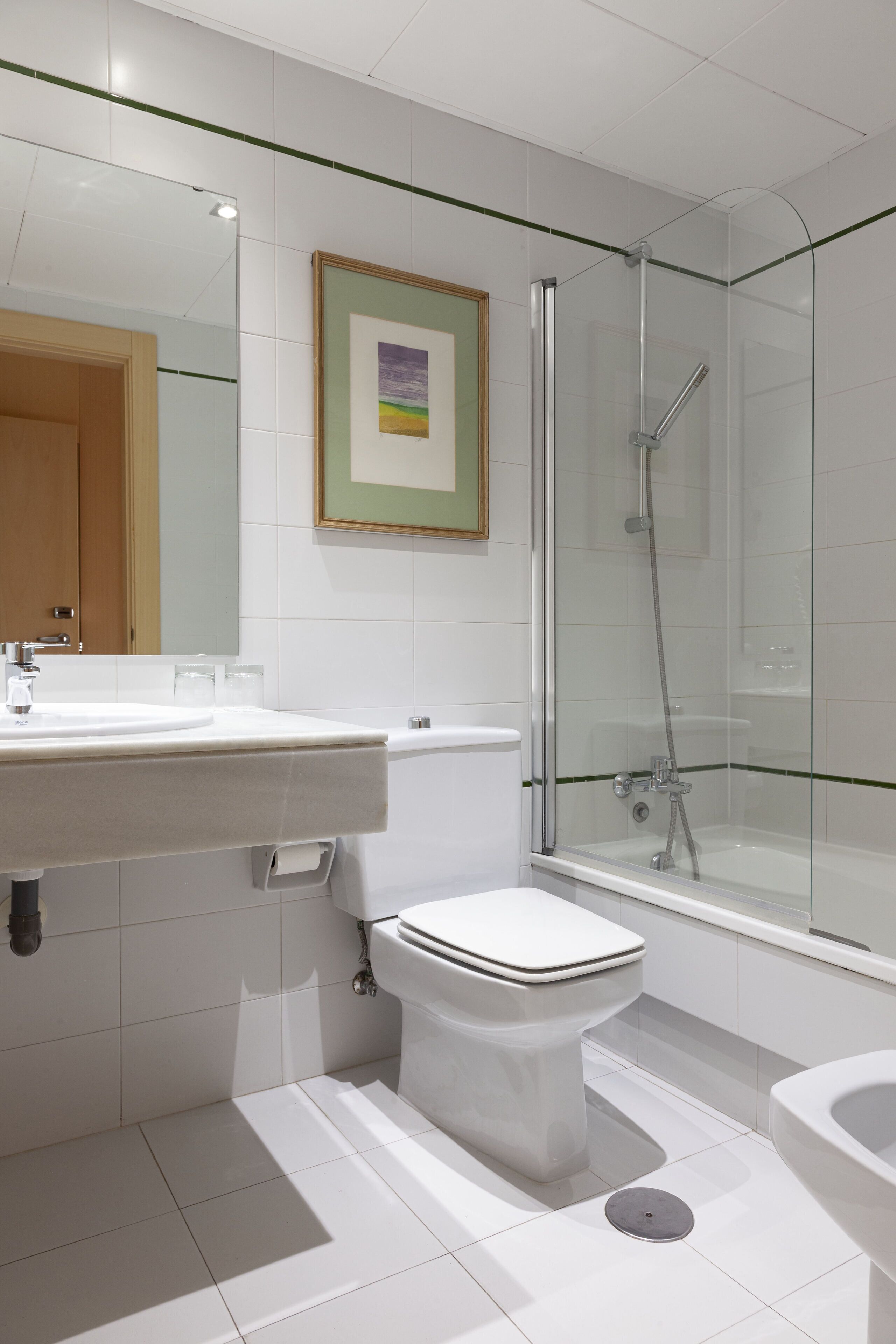 A modern bathroom with a glass-enclosed shower, a white sink, and a toilet.