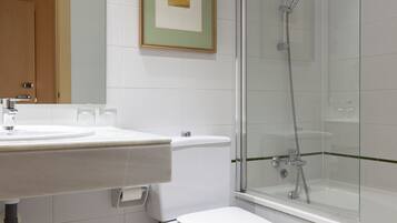 A modern bathroom with a glass-enclosed shower, a white sink, and a toilet.