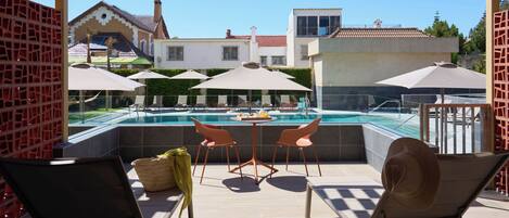 A poolside area with two chairs, a table, and umbrellas.