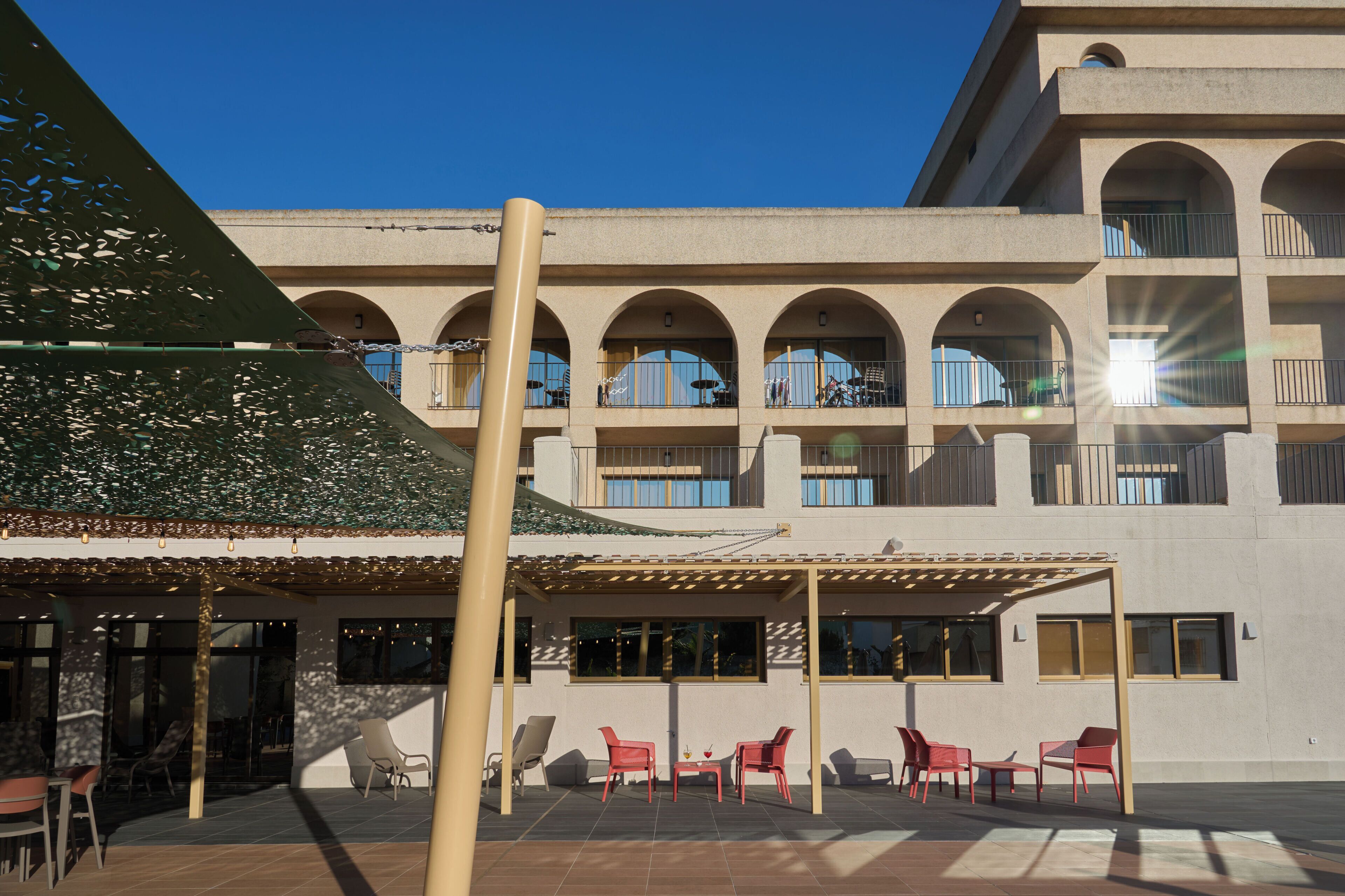 Un edificio con un patio techado, mobiliario exterior y varios balcones.