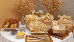Una mesa de buffet con panes, bollería y cereales varios.