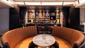 Una zona de bar con asientos curvados, una mesa de mármol y una barra bien surtida.