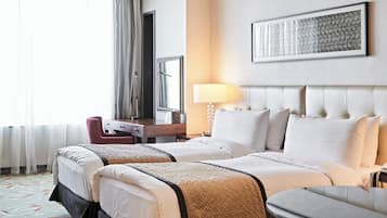 A hotel room with two beds, a desk, a chair, a lamp, and a large window with curtains.