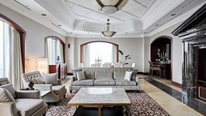 Una sala de estar amplia con un sofá grande, sillones, una mesa de centro y un comedor con candelabro.