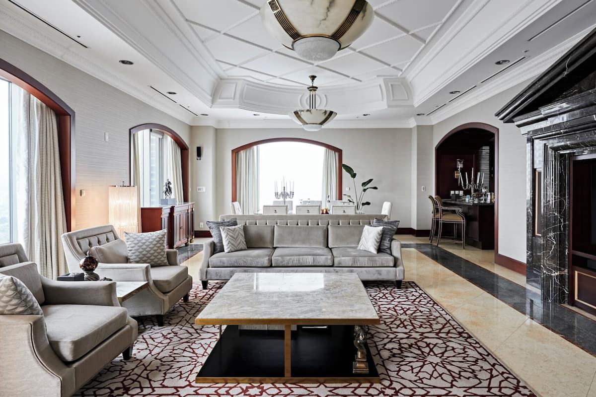 A spacious living room with a large sofa, armchairs, a coffee table, and a dining area with a chandelier.