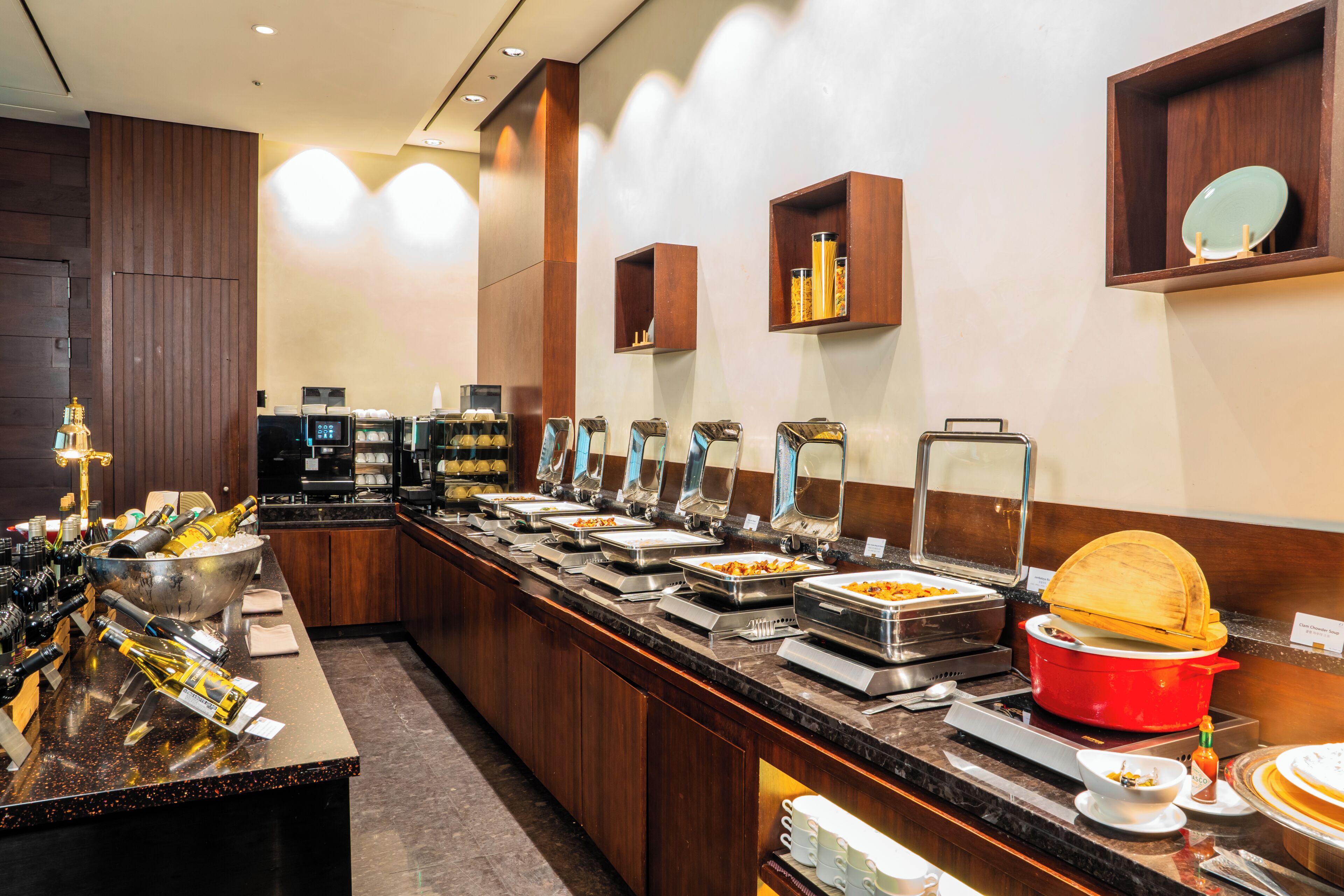 A buffet setup with various food stations, a red pot, and a microwave.