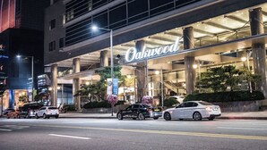 Un hotel con un letrero llamativo, varios pisos y un estacionamiento con coches.