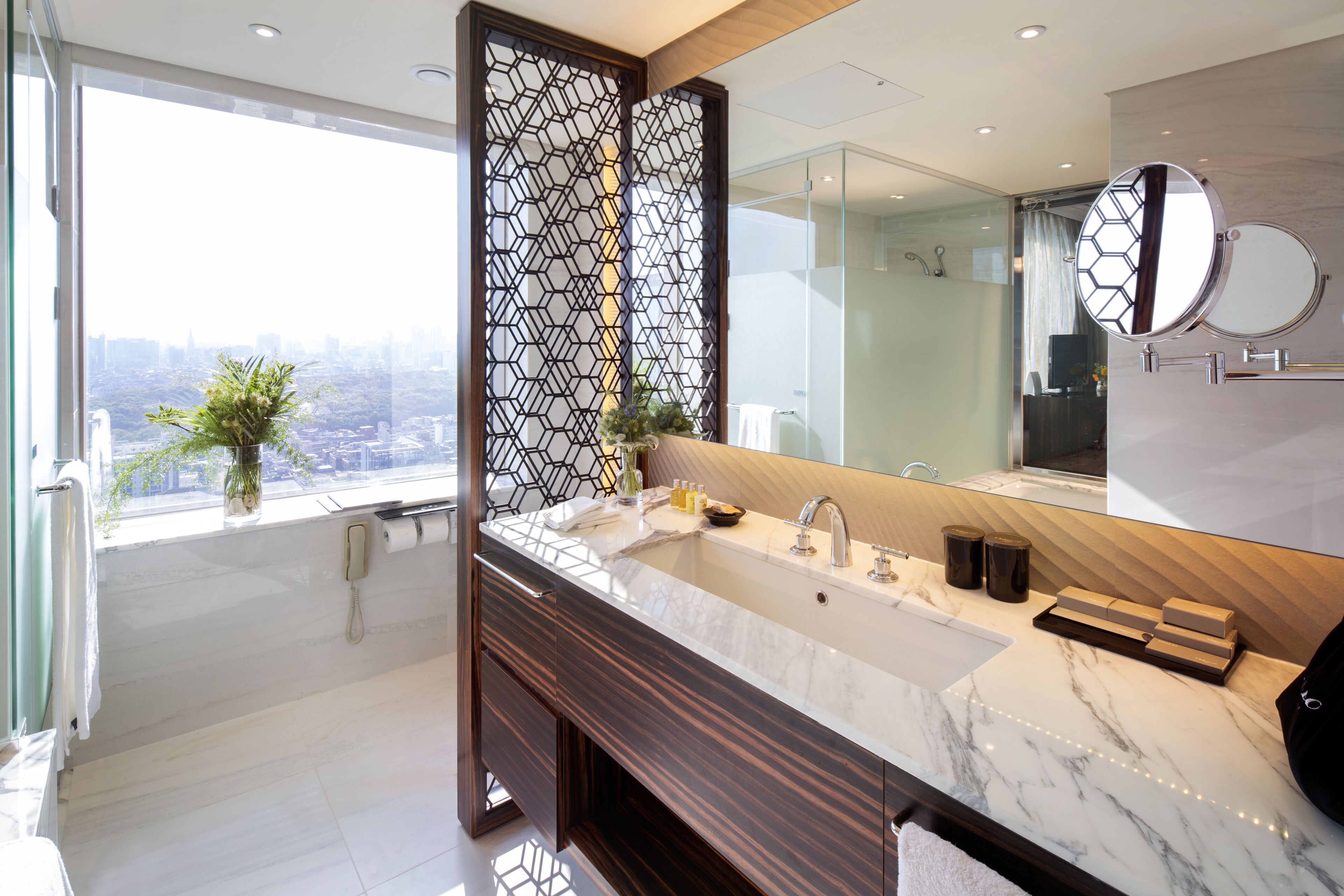 Un baño moderno con un ventanal grande, un lavamanos de mármol y un separador decorativo.