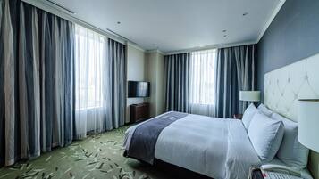 A hotel room with a bed, a TV, a bedside lamp, and a telephone.