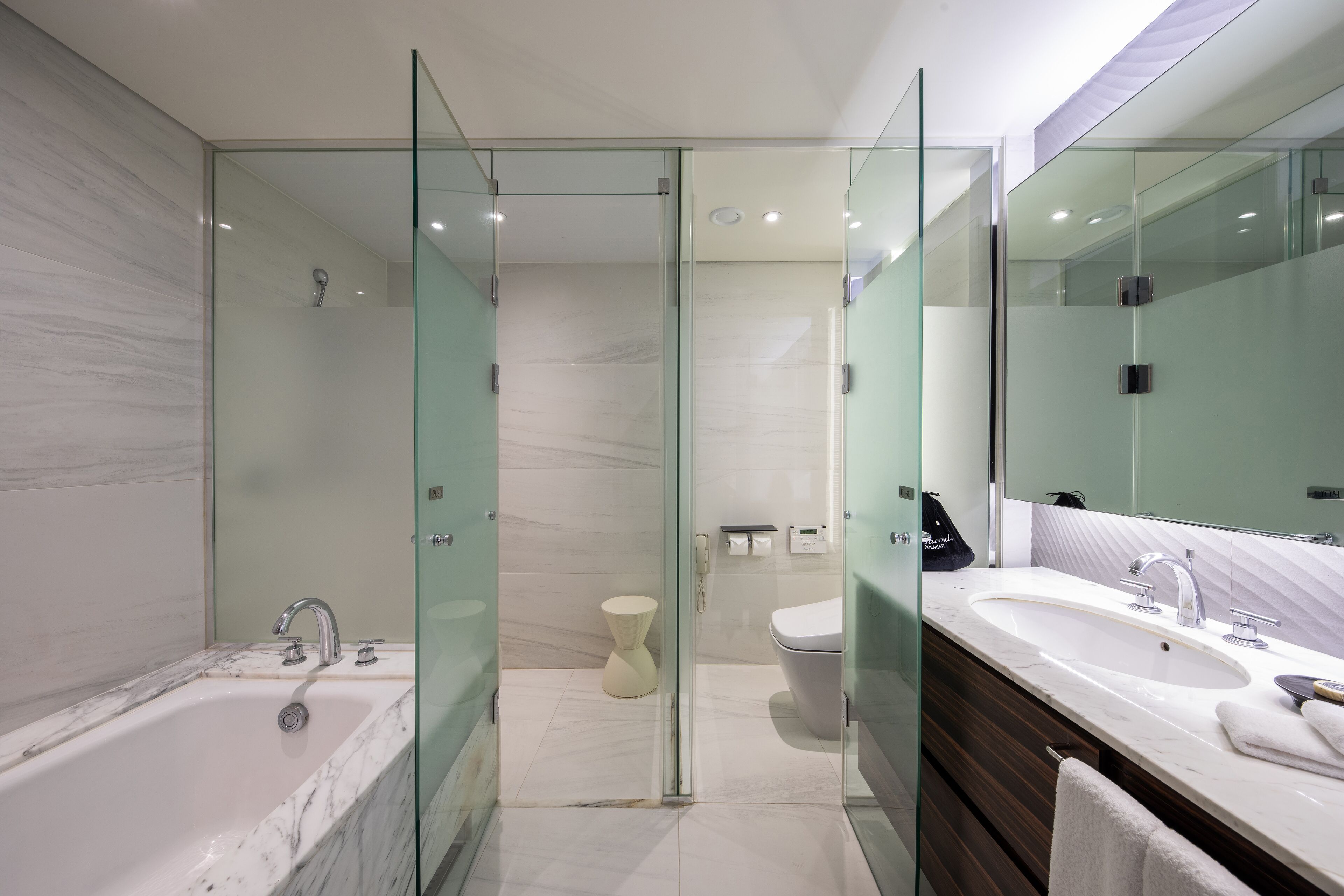 Un baño moderno con ducha envuelta en vidrio, un lavamanos grande y un tocador con espejo.