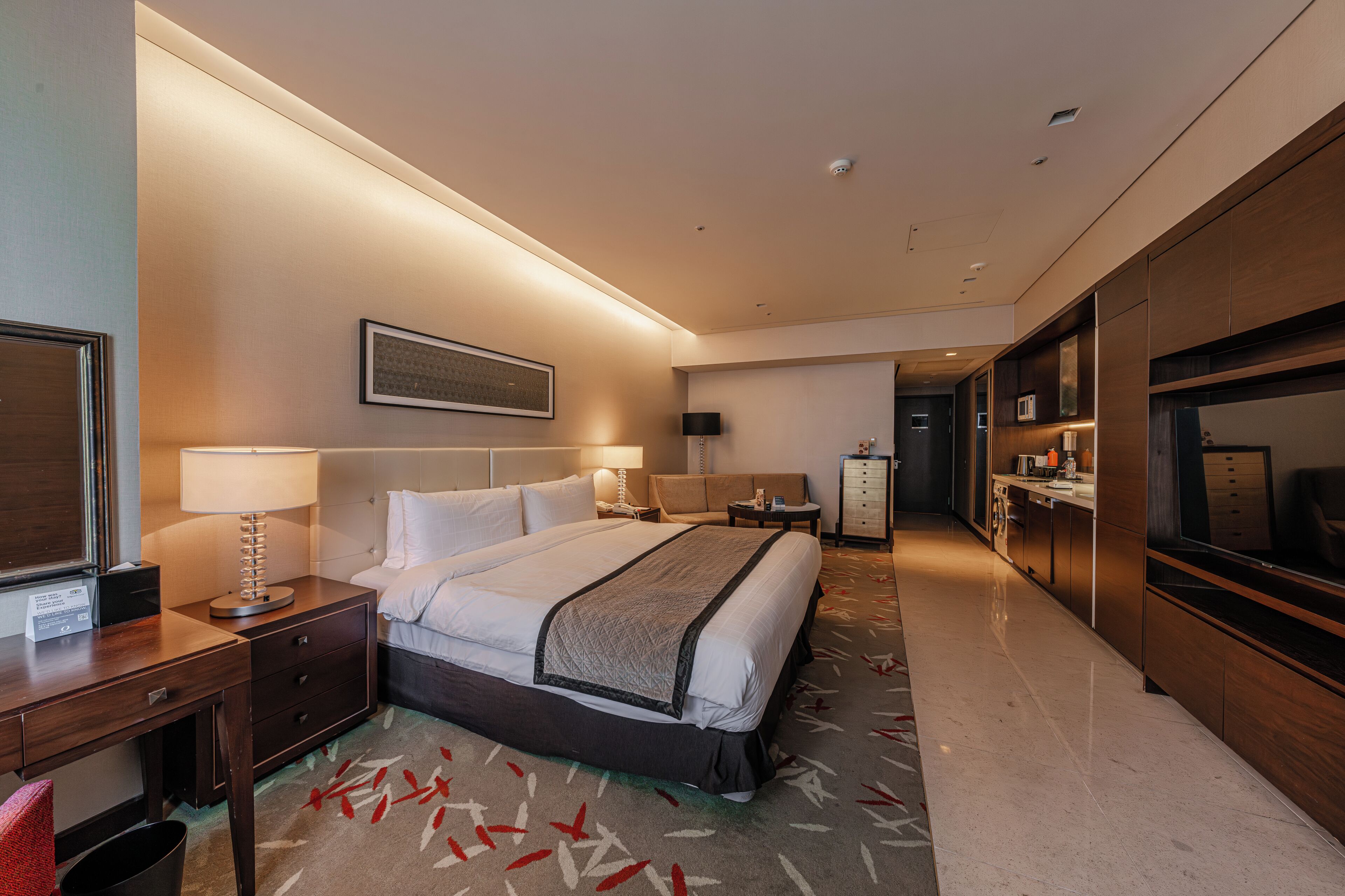 A hotel room with a bed, bedside tables, a desk, a TV, a wardrobe, and a bathroom.