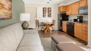 A modern living room with a sofa, a dining table with chairs, and a kitchen area with wooden cabinets and appliances. - Hilton Vacation Club Villas de Santa Fe (Santa Fe)