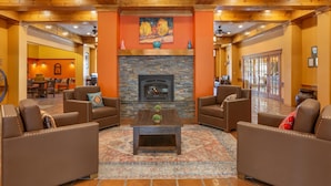 A spacious lobby with leather sofas, a central coffee table, a stone fireplace, and a colorful rug. - Hilton Vacation Club Villas de Santa Fe (Santa Fe)