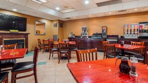 A restaurant with wooden tables and chairs, a television mounted on the wall, and a coffee machine.