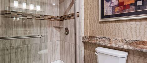 A modern bathroom with a shower, toilet, and a decorative wall piece.