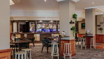 A bar area with multiple stools and tables, a bar counter with various bottles, and a carpeted floor.