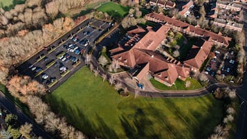 Vista aérea de uma área residencial com estacionamento, casas e um grande campo verde.
