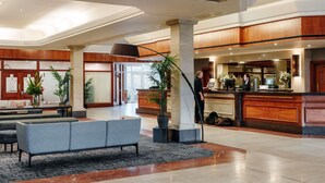 A spacious lobby with a reception desk, a seating area with a sofa, and a large plant. - Mercure Daventry Court Hotel (Daventry)