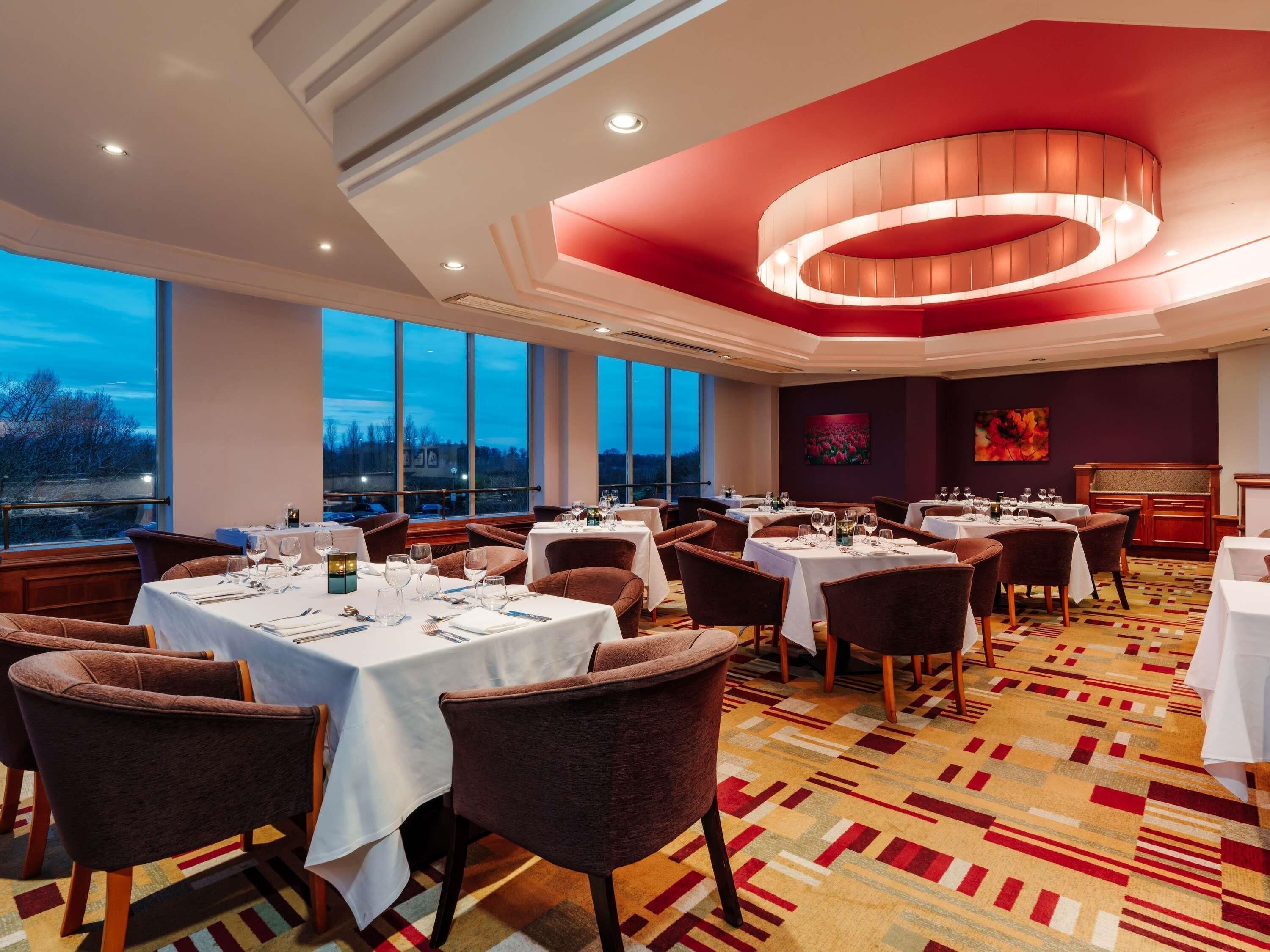 Un restaurante con mesas dispuestas para comer, amplios ventanales y vistas al exterior.
