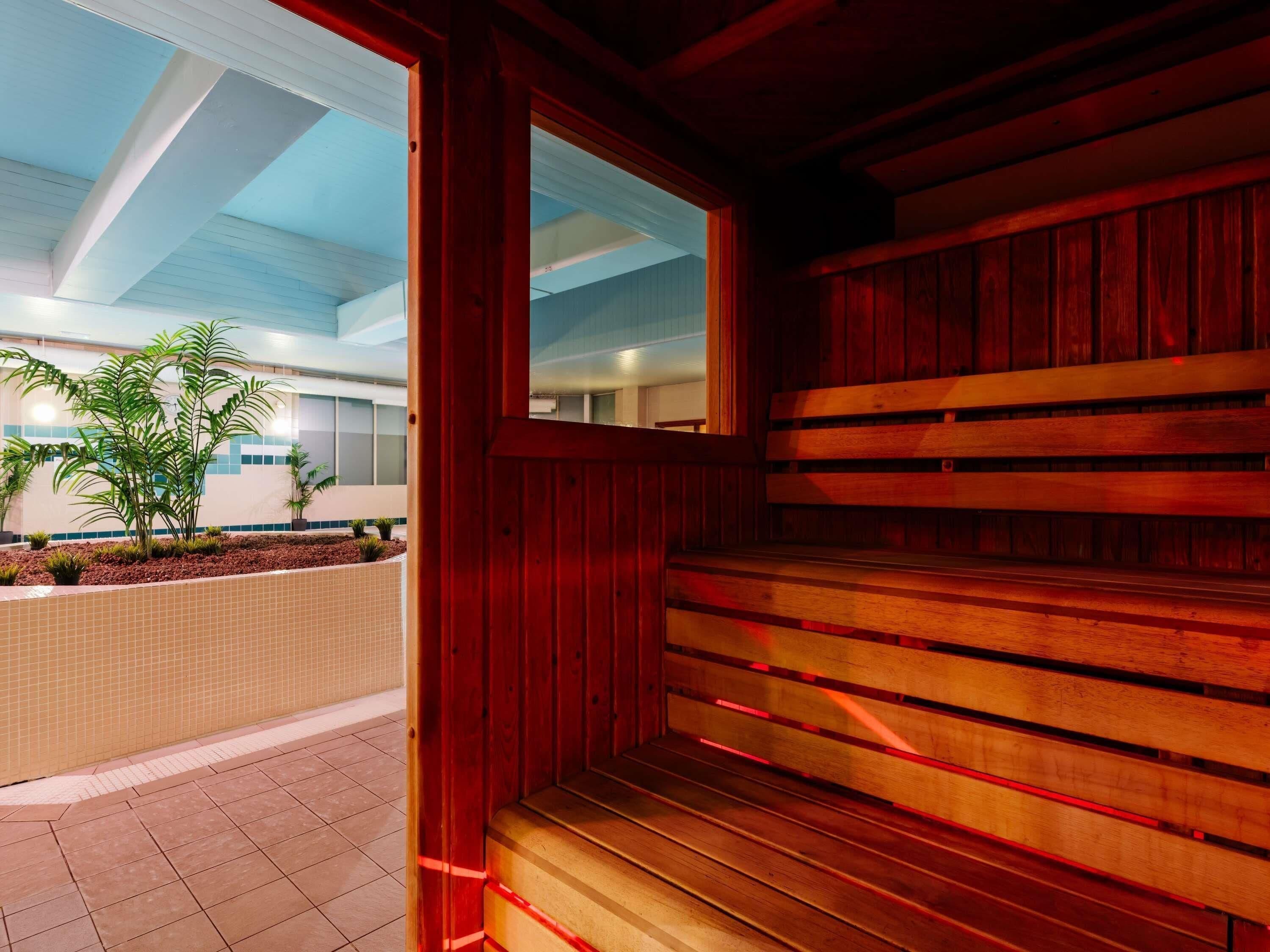 A wooden staircase leading to an upper level, a tiled floor, and a view of a building with windows and plants.