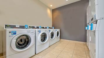 Une buanderie équipée de trois machines à laver à chargement frontal et d’un sèche-linge.