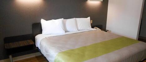 A hotel room with a bed, bedside tables, and wall-mounted lighting.