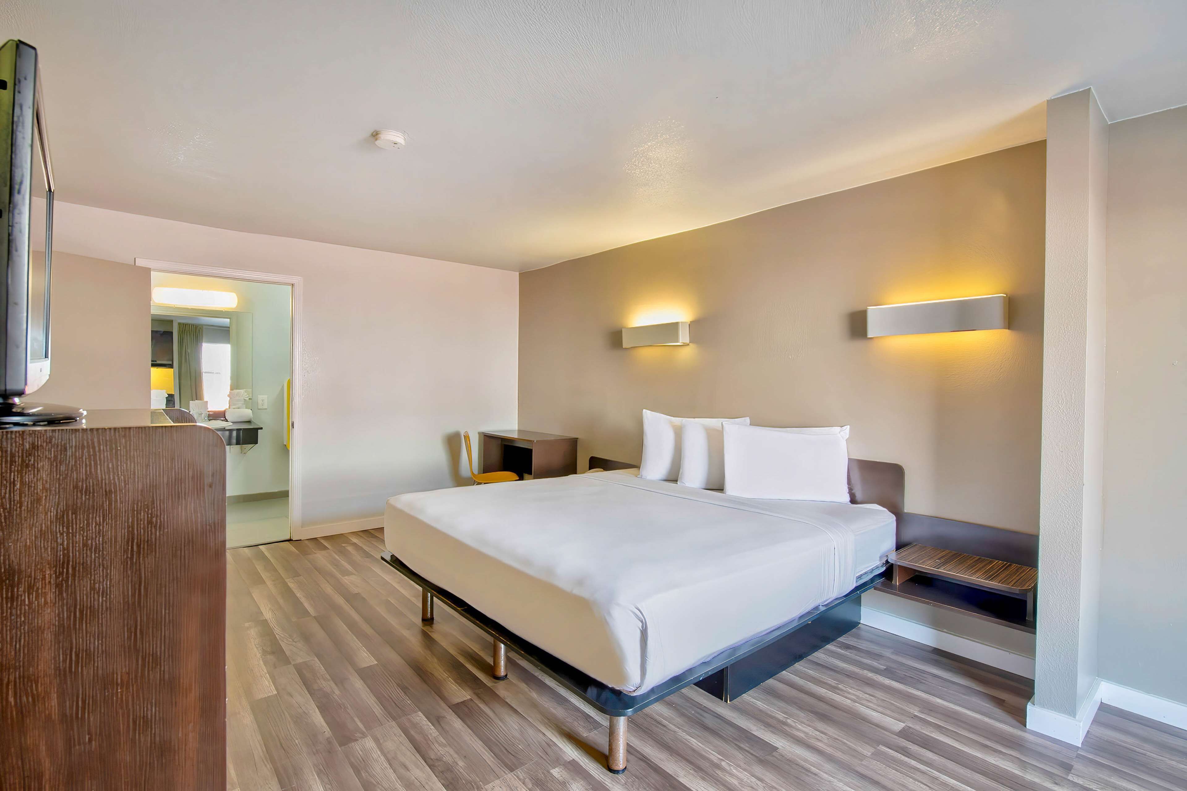 Een moderne hotelkamer met een groot bed, nachtkastjes, een bureau en een televisie.