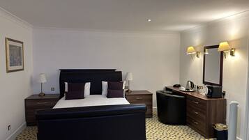 Una habitación de hotel con una cama grande, mesitas de noche, un escritorio, un espejo y un radiador.