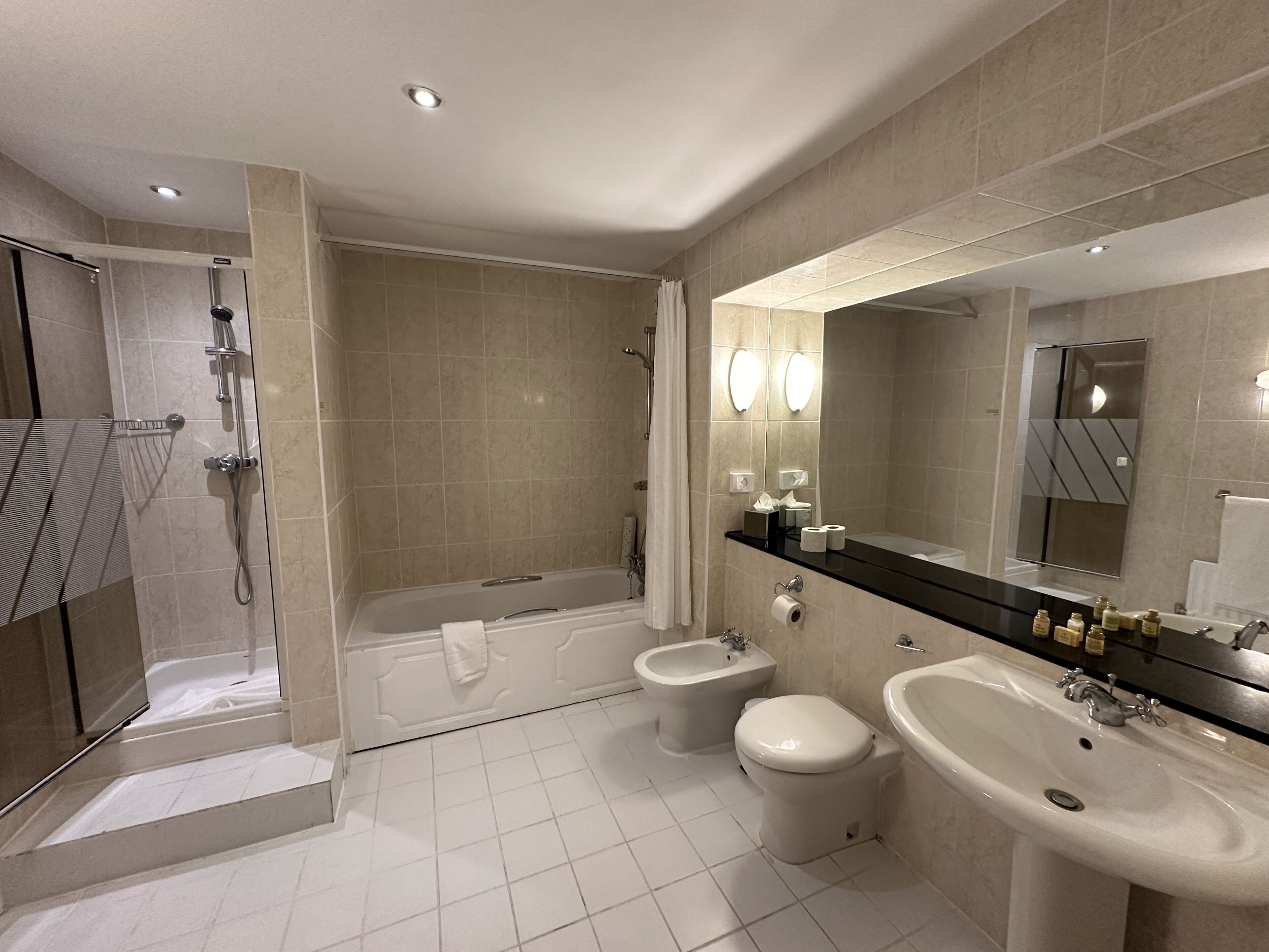 Un baño moderno con cabina de ducha, bañera, bidé y dos lavamanos.