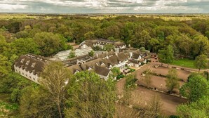 A large estate with multiple buildings, including a greenhouse, surrounded by dense trees and open fields. - Basingstoke Hotel (Hook)