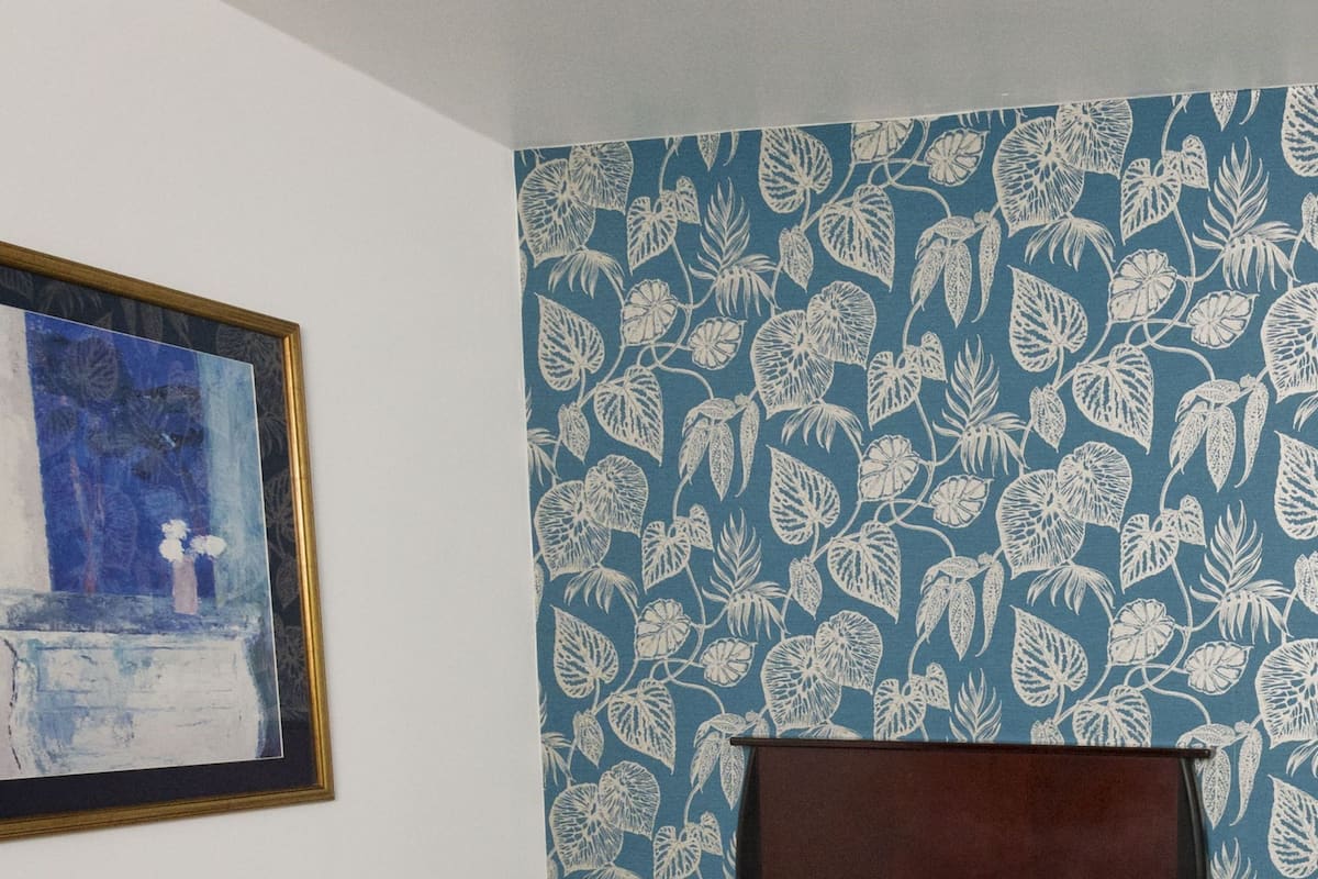 Une chambre d’hôtel avec un lit, une table de chevet, une lampe et un tableau encadré au mur.