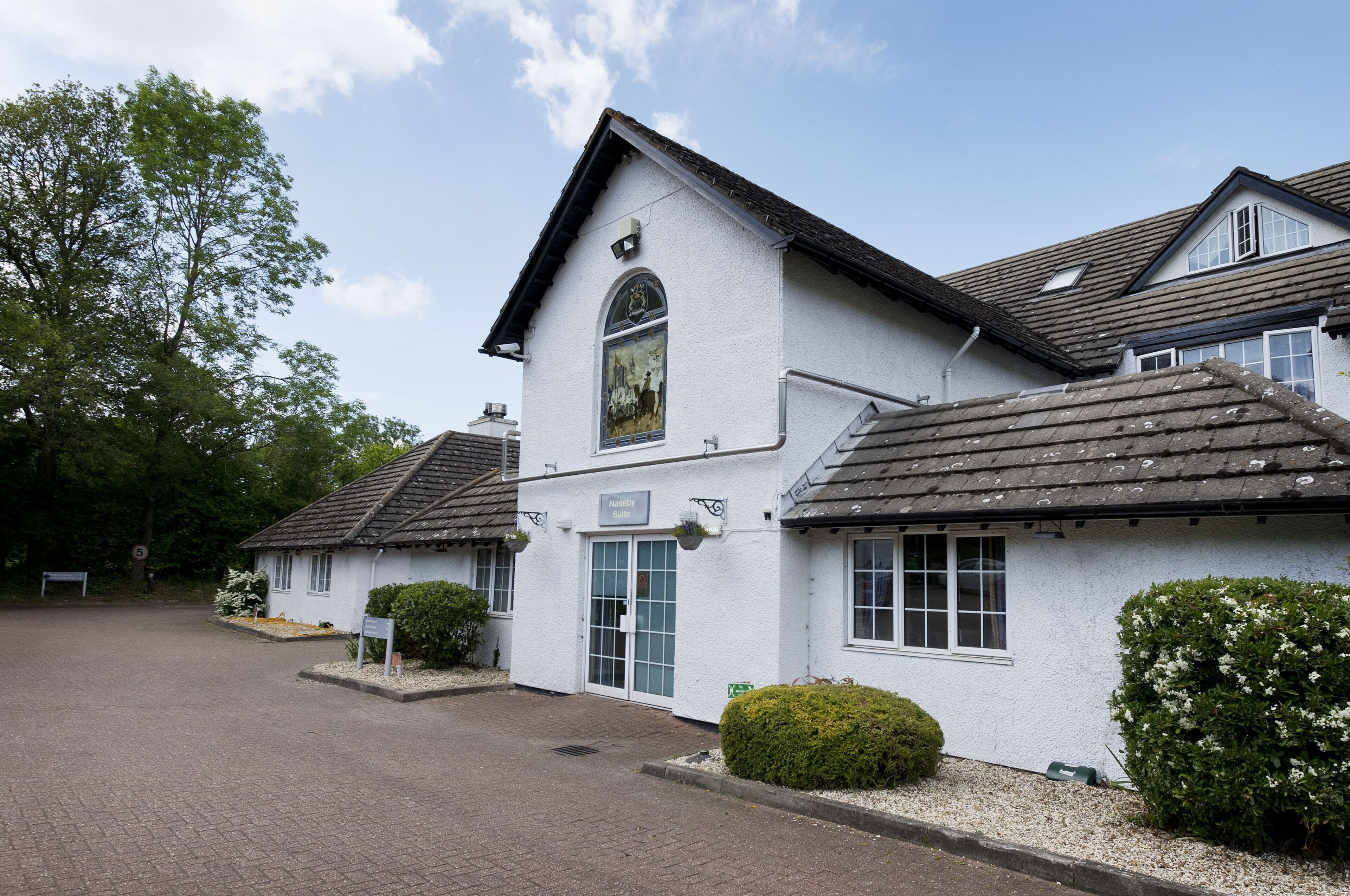 A white building with a pitched roof, a large arched window, and a sign that reads 'Nursing Suite.'