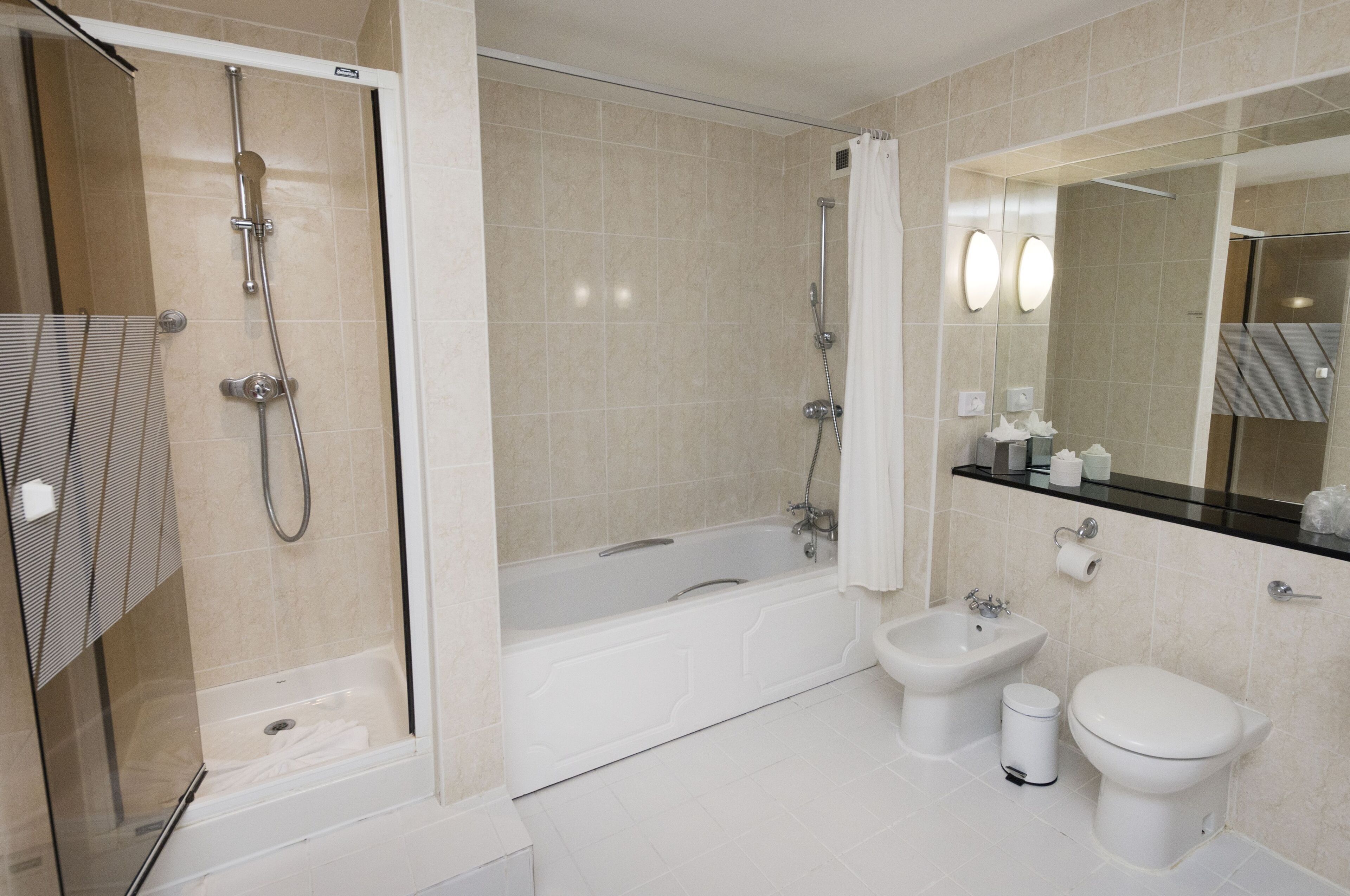 A modern bathroom with a glass-enclosed shower, a freestanding bathtub, a bidet, and a toilet.