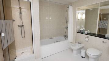 A modern bathroom with a glass-enclosed shower, a freestanding bathtub, a bidet, and a toilet.