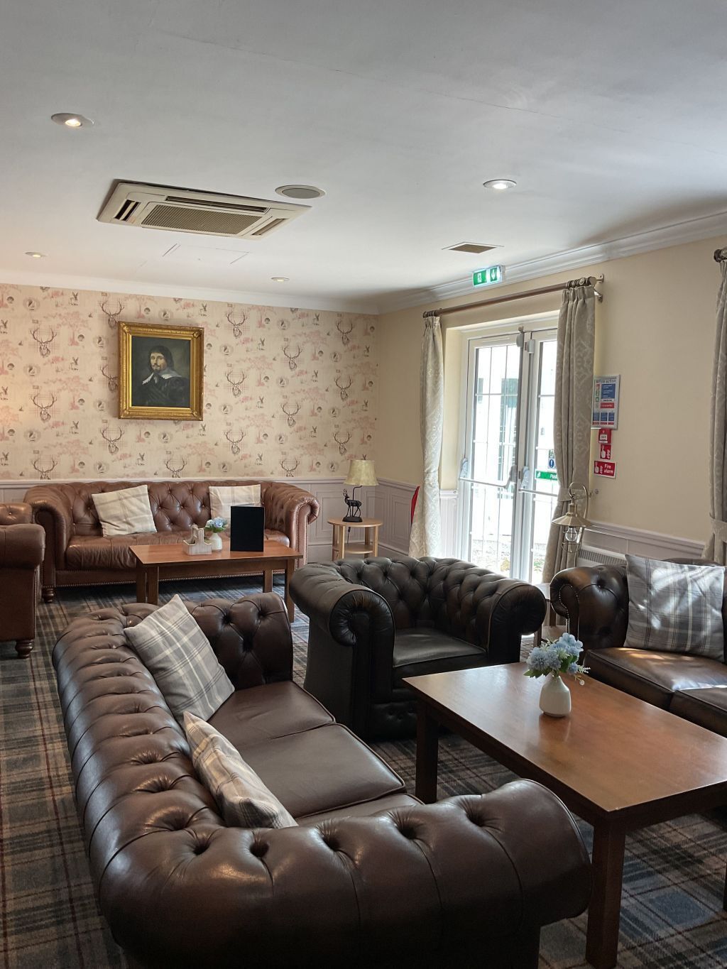 A room with a sofa, armchairs, a table, and a painting on the wall.