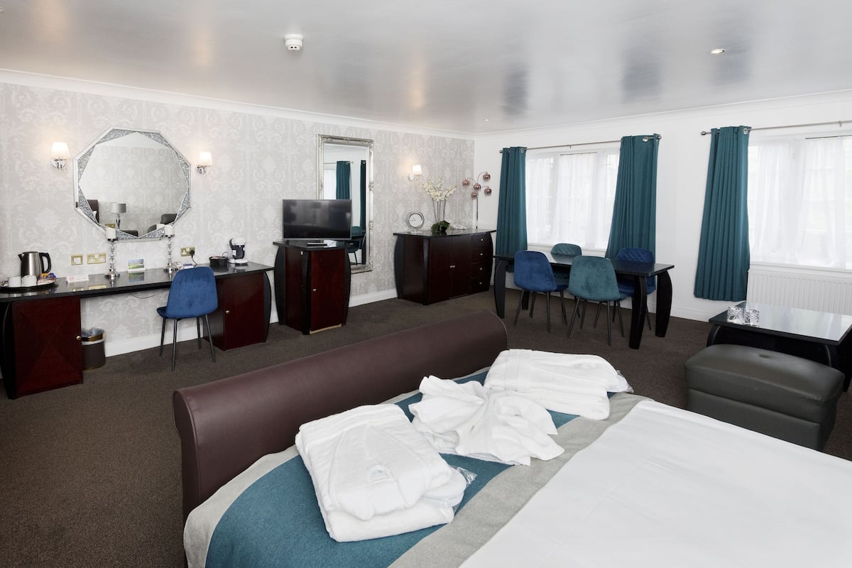 Une chambre d’hôtel équipée d’un lit, d’un bureau avec un ordinateur, d’une chaise, d’une télévision et d’un miroir.