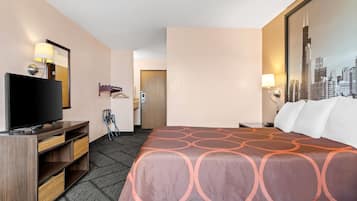 A hotel room with a bed, a TV, a desk, and a cityscape painting on the wall.