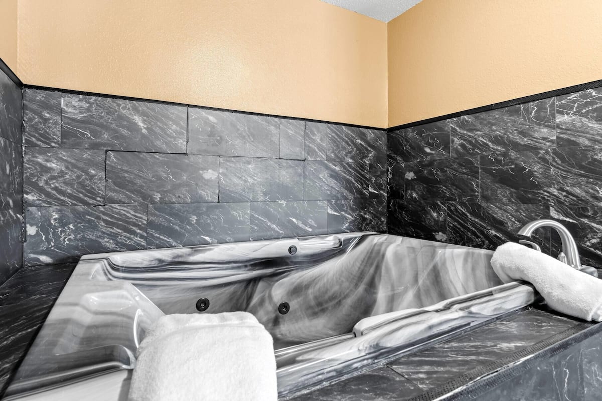 Ein modernes Badezimmer mit einer Marmorbadewanne, einem integriertem Waschbecken und einem Handtuchhalter.
