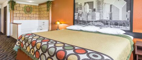 A hotel room with a bed, a cityscape painting, a sink, and a plant.