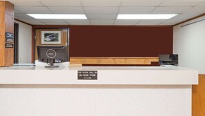 A reception desk with a sign indicating a clerk's phone number and a computer monitor. - Super 8 by Wyndham Dixon (Dixon)